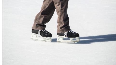 A pair of hockey skates on an ice rink.
